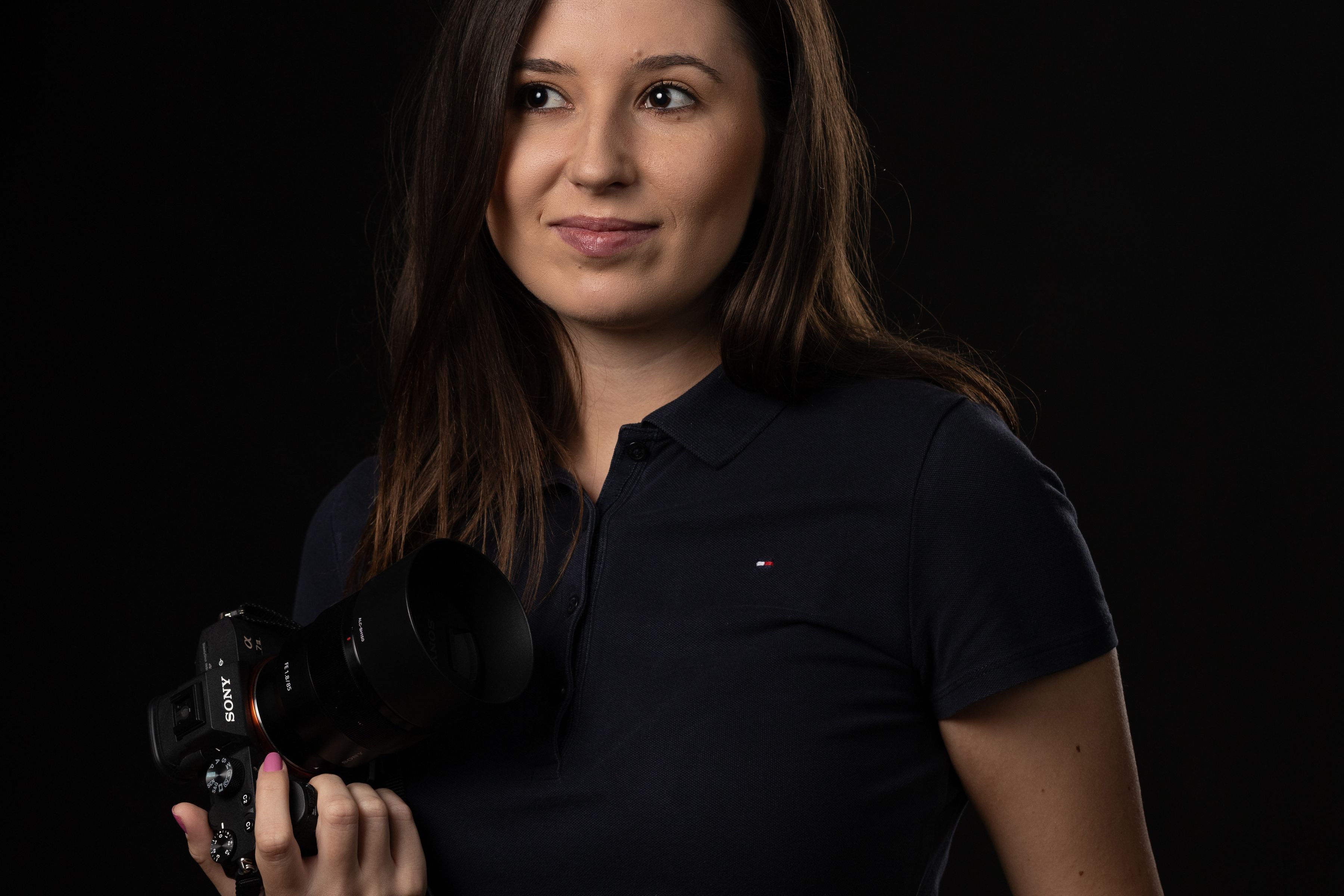 Mara Voss holding a camera in a dark studio.