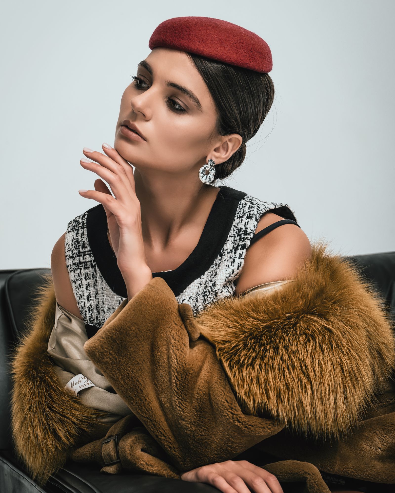 A woman in a red beret and fur coat indoors.
